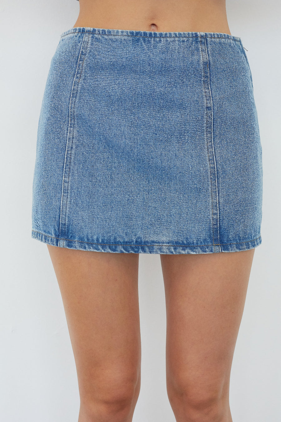 A light blue denim mini skirt worn by a model, shown from the waist down against a plain light gray background.