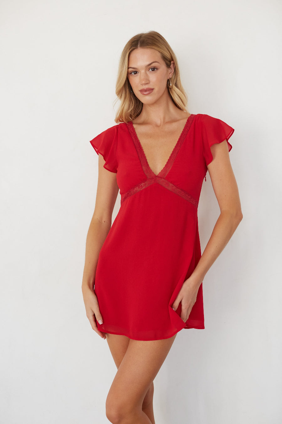 Woman wearing a red dress with ruffled sleeves on a white background