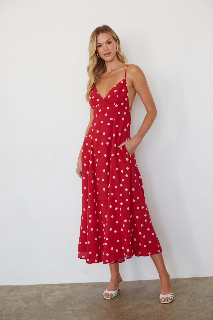 Woman wearing a red polka dot dress against a white background
