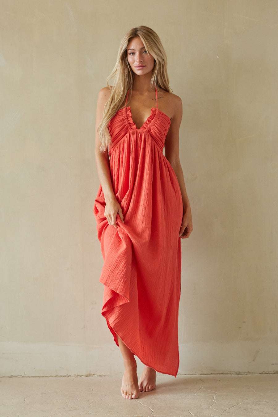 red-image | Woman wearing a coral dress against a beige background