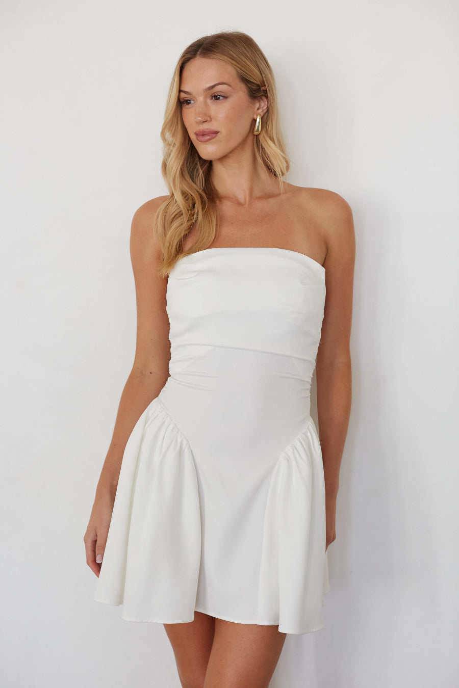 white-image | Woman wearing a white strapless dress against a plain background