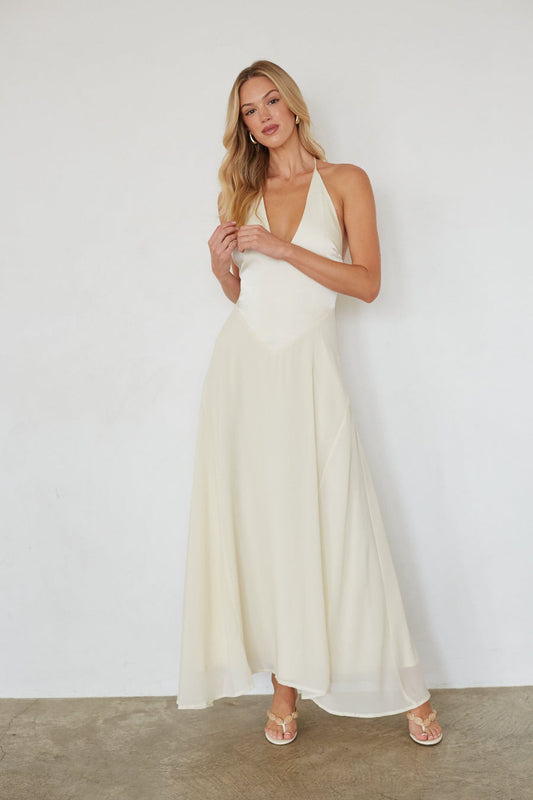Woman wearing a white halter neck dress against a plain background